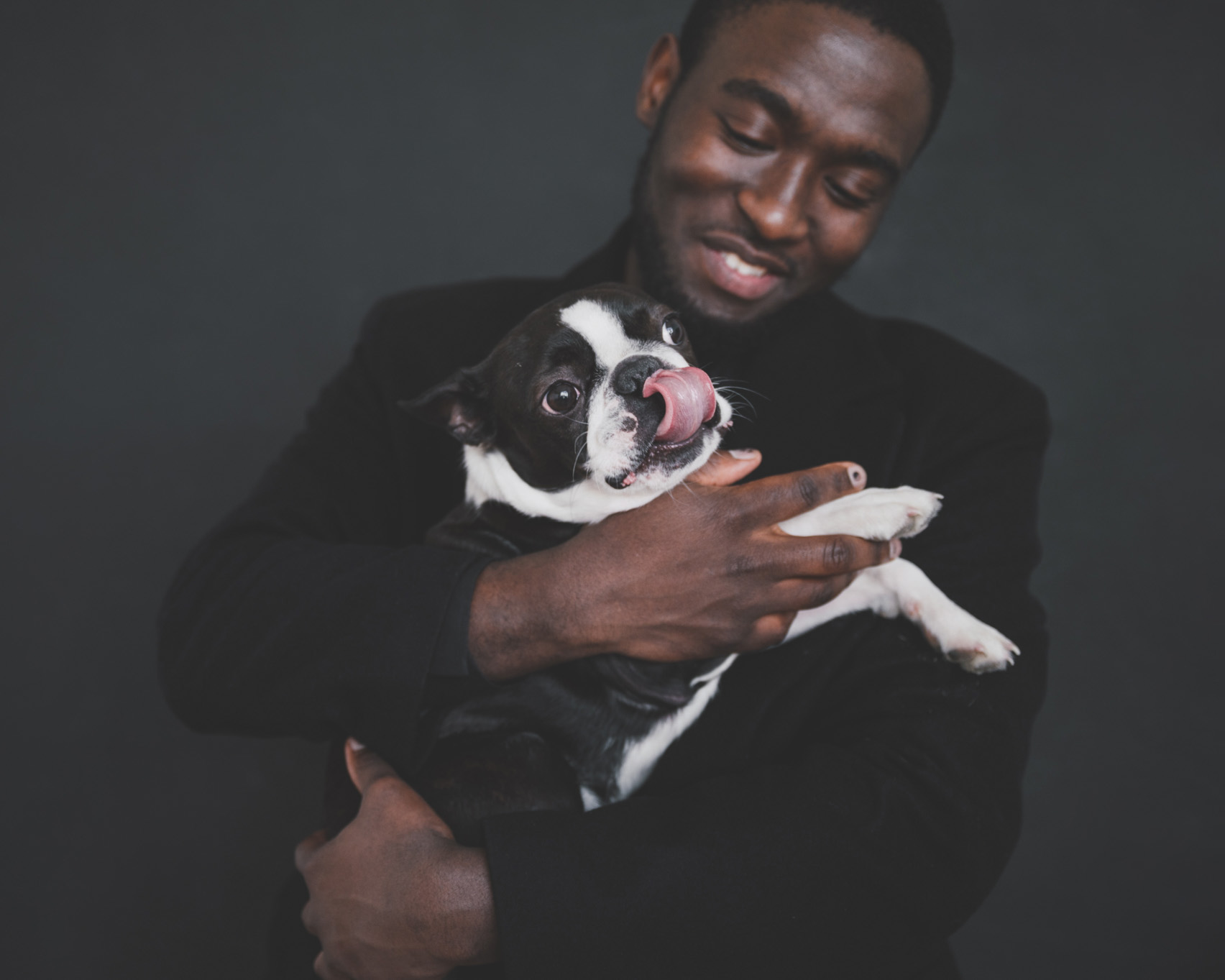 A man holding a pug licking its lips